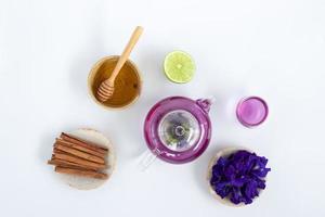 vista superior del té de flor de guisante de mariposa con limones sobre fondo blanco. concepto de bebida saludable foto