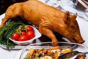 lechón asado sobre lecho de lechuga. mesa de buffet foto