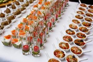 Little glasses with fresh salads stand on white table photo