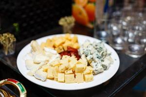 Cheese plates served with grapes, jam, and nuts on a wooden board.Top view photo