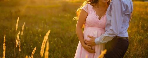 pareja feliz, futuros padres, besándose en un campo abierto al atardecer. hombre abrazando a su mujer embarazada. comenzando un concepto de familia. foto