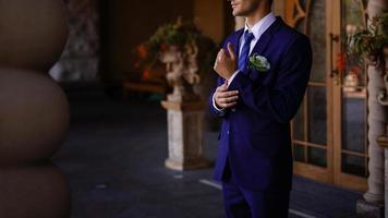 A young man in a suit straightens his tie photo