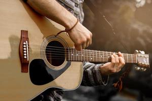 joven músico tocando la guitarra acústica de cerca foto