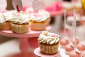 cupcakes de vainilla coronados con un remolino de glaseado de vainilla dulce capturados en la mesa en un día soleado. foto