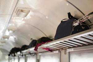 Three adjacent empty seats in modern European train with luggage on shelf, portrait vertical orientation. Holiday vacation, tourism, travel, modern train interior, or railway transportation concept photo