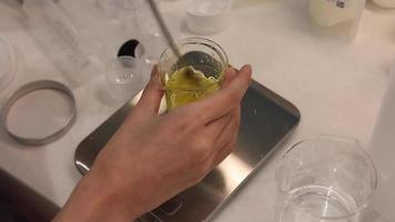 mezcle el aceite y la cera de abejas en el vaso de precipitados con una cuchara, pese los ingredientes en la báscula electrónica del laboratorio