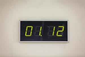 reloj digital negro sobre un fondo blanco que muestra la hora 01.12 foto