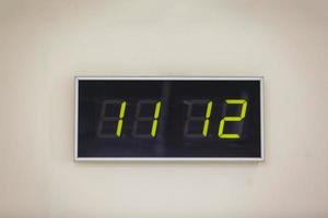 Black digital clock on a white background showing time eleven hours twelve minutes photo