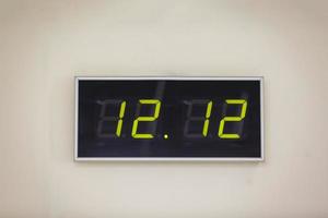 Black digital clock on a white background showing time twelve hours twelve minutes photo