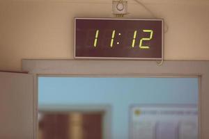 Black digital clock on a white background showing time eleven hours twelve minutes photo