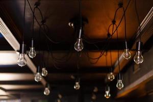 Retro Edison orange bulb design on Spider chandelier, easily hanging by black wires from ceiling. photo