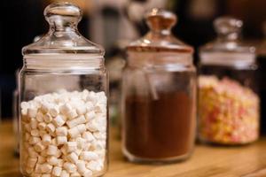 Details of a tasty candy bar with jugs of sweets, cookies and marshmallows photo