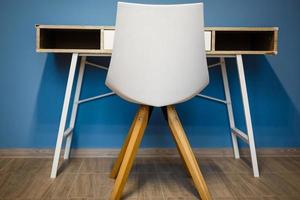 pared azul en un sencillo comedor escandinavo con una silla de mesa comunal de madera y blanca foto