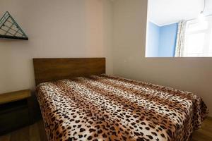 Dormitorio en tonos suaves con ropa de cama de color marfil, almohadas y manta naranja. Habitación decorada con mimbre. foto