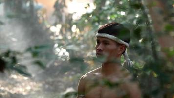 Young male wearing head and both of his hands wrapped in twisted hemp rope, martial arts dance before the martial arts of Thai boxing, Blurred elephants and spreading white mist in background