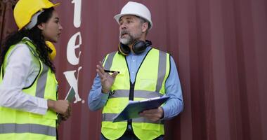 Handheld panning shot, middle-aged Caucasian business engineer man and pretty secretary female checking transport container, They are walk and talking and write into report paper on clipboard video