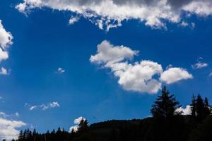 los parapentes vuelan cerca de una gran nube. muchos paracaídas en el cielo. muchos parapentes vuelan en el cielo soleado. parapente foto