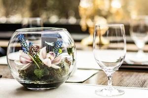 vasos vacíos colocados en vasos de restaurante en el restaurante sobre las flores de la mesa foto