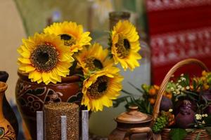 Bouquet of sunflowers in old clay jug. In the foreground branches with ripe cherry plum photo