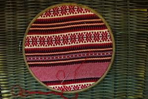 The wooden hoop with the embroidery pattern of red and Black color on canvas. Slavic Embroidery with hemming. photo