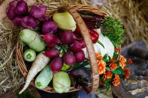 Basket with organic vegetables on the green grass and flowers. Outdoors. freshly harvested vegetables. raw vegetables in wicker basket.basket with Vegetables and Flowers photo