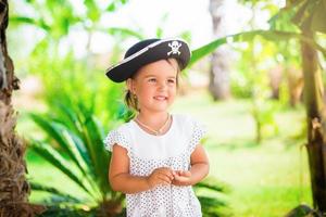 hermosa niñita con sombrero pirata con una calavera sosteniendo una estrella de mar en la playa foto