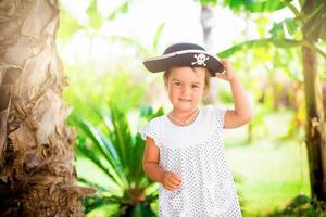 hermosa niñita con sombrero pirata con una calavera sosteniendo una estrella de mar en la playa foto