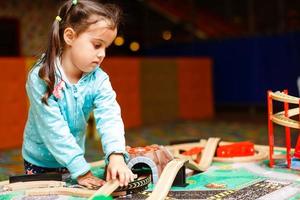 Joyful girl playing with toy railway photo