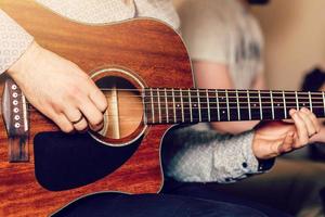 joven músico tocando la guitarra acústica de cerca foto