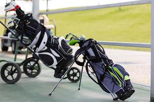 Golf bag with clubs on green field, close up photo