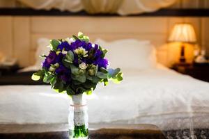 Image of a beautiful floral bouquet on wood table on the background of a chic bed photo