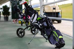 Golf bag with clubs on green field, close up photo