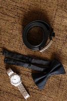 Groom wedding accessories. cufflinks, belt and watch with boutonniere on table photo