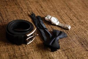 Close up of modern groom accessories. wedding rings, black necktie, leather shoes and watch photo