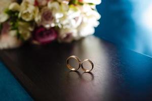 detalles de la mañana del día de la boda. dos anillos de boda dorados están sobre la mesa de madera marrón foto