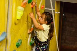 little girl climbing a rock wall indoor photo