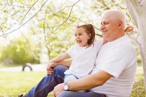 grandfather and his little granddaughter together in garden photo