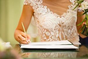 la novia escribe con un bolígrafo, un primer plano de la mano de una mujer escribiendo en papel foto