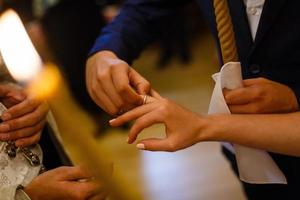 Groom slipping ring on finger of bride at wedding photo