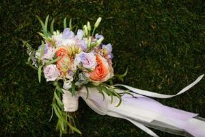 Bridal bouquet. The bride's bouquet. Bouquet of white, pink and green colors with silk ribbons of pastel color on grass background photo