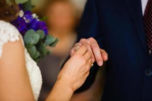 los recién casados intercambian anillos, el novio pone el anillo en la mano de la novia en la oficina de registro matrimonial foto