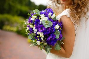 bridal bouquet blue with white flowers in the bride's hands. photo