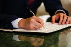 Closeup of a businessman's hands while writing some documents photo