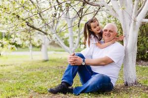 grandfather and his little granddaughter together in garden photo