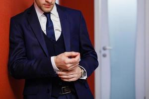 Man on red background adjusts suit photo