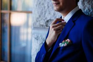 elegante traje azul de hombre de negocios, endereza su corbata en un hotel caro, yendo a una reunión foto
