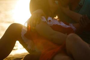 pareja joven sentada en la playa. puesta de sol foto