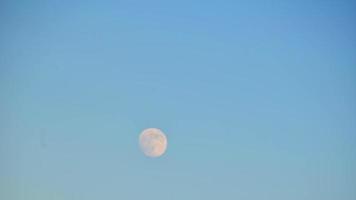transizione lunare attraverso il cielo con cielo blu chiaro e copertura nuvolosa. condizioni meteorologiche mutevoli guardando la luna video