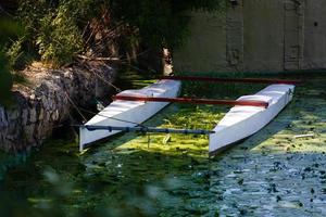Piece of a catamaran on a green river background photo