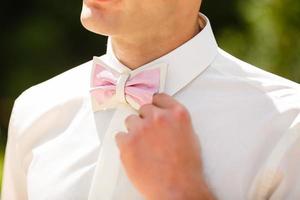 Close-up of a man's suit and a pink butterfly. Decorating flowers on a light suit. Outdoor photo